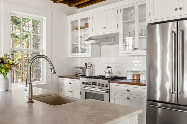 286 Atlantic Hwy, Northport, ME 04849 - kitchen with stainless steel appliances, ventilation hood, a sink, decorative backsplash, and white cabinetry