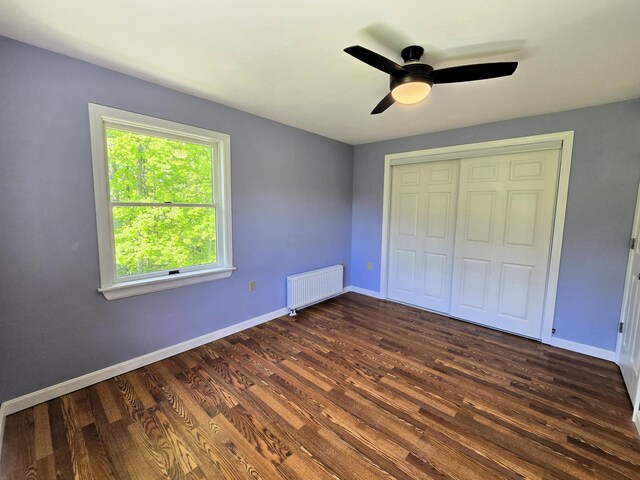 237 Bangor Rd, Unity, ME 04988 - unfurnished bedroom with radiator heating unit, dark wood-type flooring, baseboards, a closet, and ceiling fan