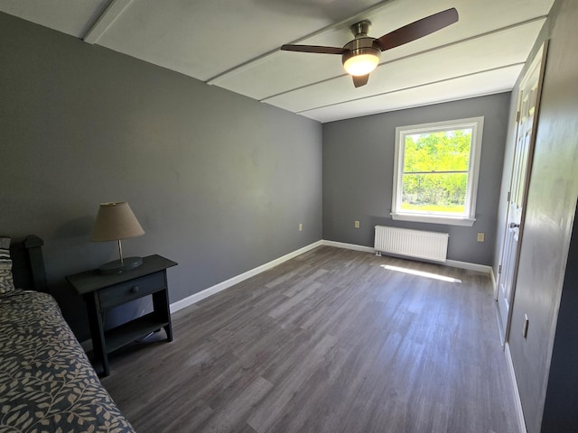 237 Bangor Rd, Unity, ME 04988 - unfurnished bedroom with radiator heating unit, dark wood-type flooring, baseboards, and a ceiling fan
