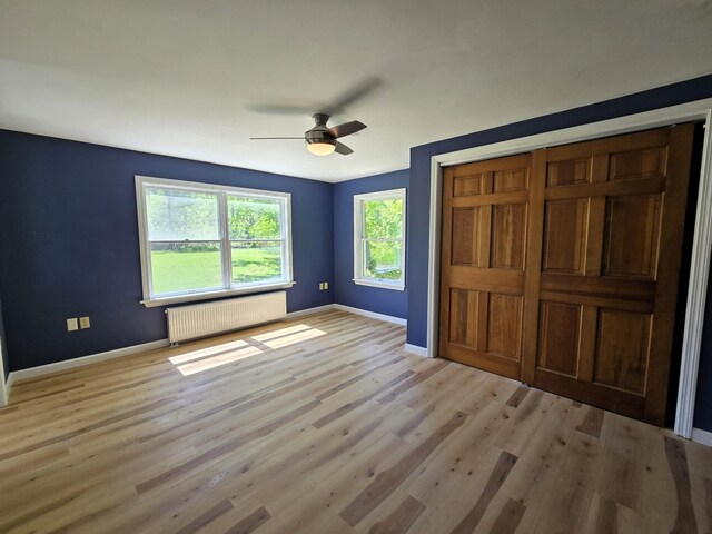 237 Bangor Rd, Unity, ME 04988 - unfurnished bedroom with radiator, baseboards, light wood-style flooring, and ceiling fan