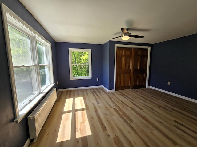 237 Bangor Rd, Unity, ME 04988 - unfurnished bedroom with radiator heating unit, baseboards, a closet, light wood finished floors, and a ceiling fan