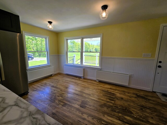 237 Bangor Rd, Unity, ME 04988 - unfurnished dining area featuring radiator, a wainscoted wall, dark wood-style flooring, and healthy amount of natural light