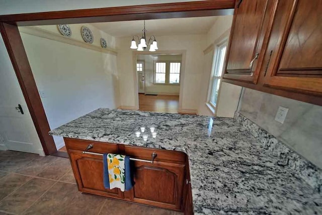 6 Pleasant Ct, Houlton, ME 04730 - kitchen with a peninsula, a chandelier, brown cabinets, light stone countertops, and decorative light fixtures