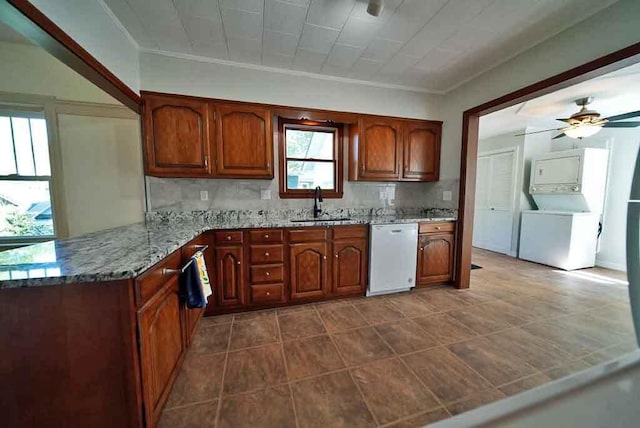 6 Pleasant Ct, Houlton, ME 04730 - kitchen with white dishwasher, stacked washer / drying machine, a sink, light stone counters, and brown cabinets