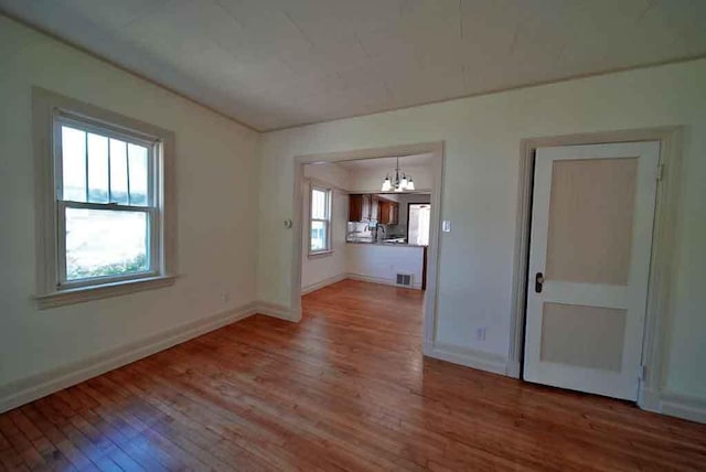6 Pleasant Ct, Houlton, ME 04730 - unfurnished living room featuring hardwood / wood-style flooring, a chandelier, and baseboards