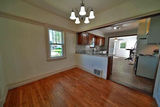 6 Pleasant Ct, Houlton, ME 04730 - kitchen with stove, a sink, hardwood / wood-style flooring, a chandelier, and a peninsula