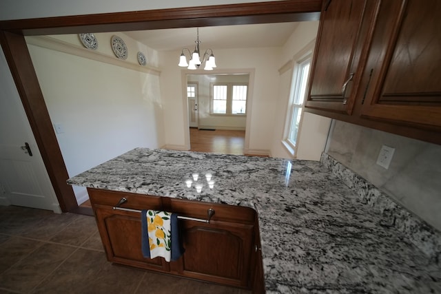 6 Pleasant Ct, Houlton, ME 04730 - kitchen featuring a peninsula, a chandelier, light stone counters, decorative light fixtures, and dark tile patterned flooring