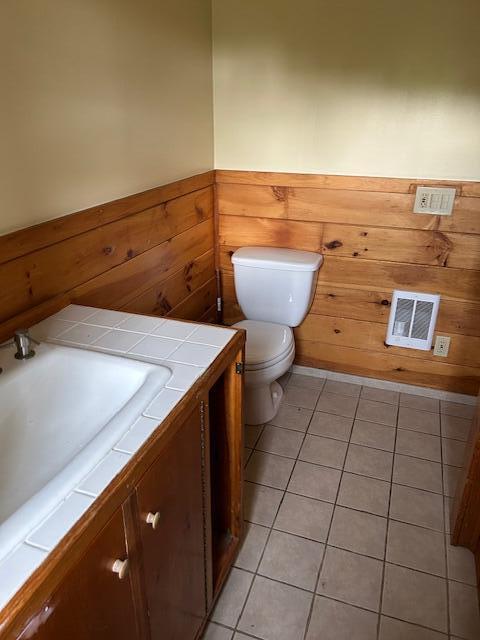 20 Monument Rd, Abbot, ME 04406 - half bath with toilet, vanity, a wainscoted wall, tile patterned flooring, and wood walls