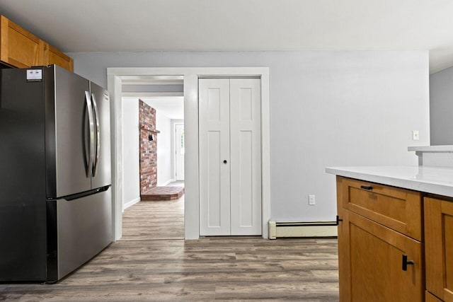 30 Ring Landing Rd, Casco, ME 04015 - kitchen featuring freestanding refrigerator, baseboard heating, wood finished floors, and brown cabinetry