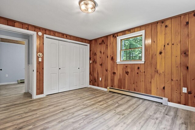 30 Ring Landing Rd, Casco, ME 04015 - unfurnished bedroom with a baseboard radiator, baseboards, wood finished floors, a closet, and wood walls