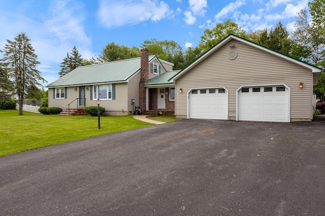 18 Tibbetts Ln, Lyman, ME 04002 - view of front of property with asphalt driveway, an attached garage, a chimney, metal roof, and a front yard