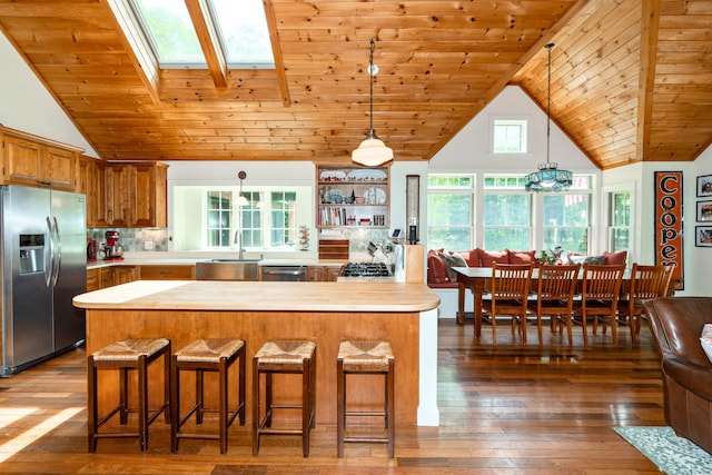 10 Pemasong Ln, Yarmouth, ME 04096 - kitchen with stainless steel appliances, light countertops, wood ceiling with exposed beams, brown cabinetry, and decorative light fixtures