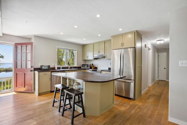 142 Fortunes Rocks Rd, Biddeford, ME 04005 - kitchen with appliances with stainless steel finishes, under cabinet range hood, light wood-type flooring, recessed lighting, and a breakfast bar