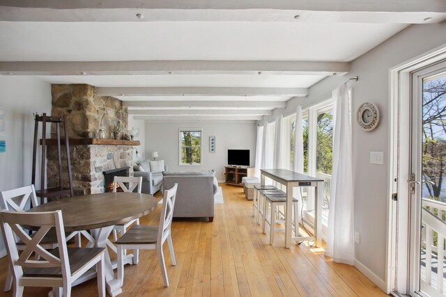 142 Fortunes Rocks Rd, Biddeford, ME 04005 - dining room featuring light wood-style flooring, healthy amount of natural light, beamed ceiling, a stone fireplace, and baseboards