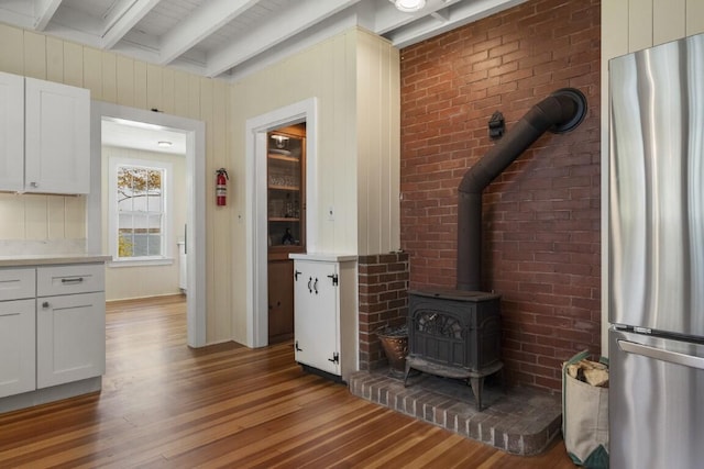 1 Mouse Is, Southport, ME 04576 - unfurnished living room featuring wood finished floors, beamed ceiling, and a wood stove