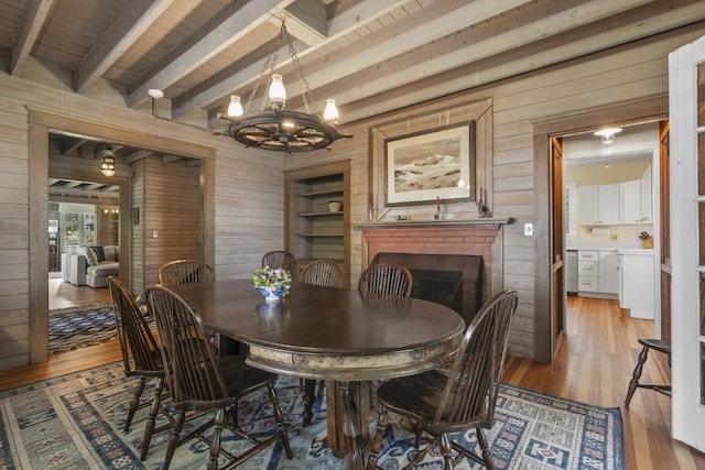 1 Mouse Is, Southport, ME 04576 - dining area featuring wooden walls, light wood-type flooring, a chandelier, beam ceiling, and a fireplace