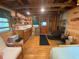 254 Eaton Rd, Dexter, ME 04435 - kitchen featuring light wood finished floors, a wood stove, brown cabinets, light countertops, and a sink