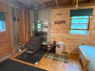 254 Eaton Rd, Dexter, ME 04435 - misc room with plenty of natural light, hardwood / wood-style flooring, wooden walls, and a wood stove
