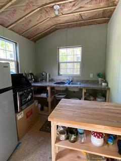 254 Eaton Rd, Dexter, ME 04435 - kitchen featuring freestanding refrigerator, healthy amount of natural light, a sink, lofted ceiling, and open shelves