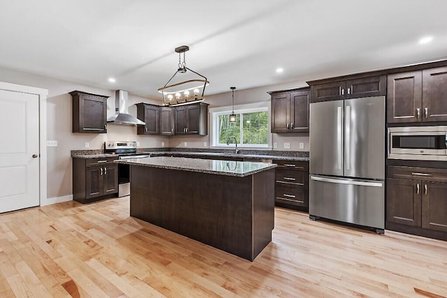 65 May Way, Sidney, ME 04330 - kitchen with stainless steel appliances, wall chimney range hood, dark brown cabinets, a sink, and light wood-style flooring