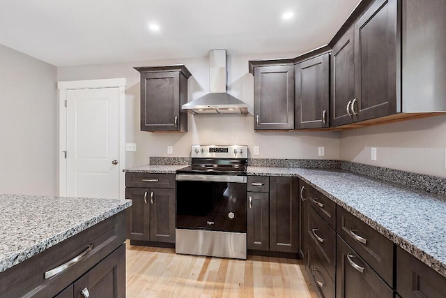 65 May Way, Sidney, ME 04330 - kitchen featuring wall chimney exhaust hood, electric range, dark brown cabinets, light wood-style flooring, and light stone counters