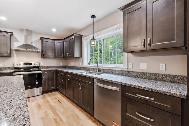 65 May Way, Sidney, ME 04330 - kitchen featuring appliances with stainless steel finishes, wall chimney exhaust hood, a sink, dark brown cabinetry, and light wood-style floors