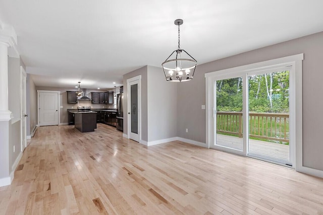 65 May Way, Sidney, ME 04330 - unfurnished living room with a chandelier, light wood finished floors, baseboards, and ornate columns