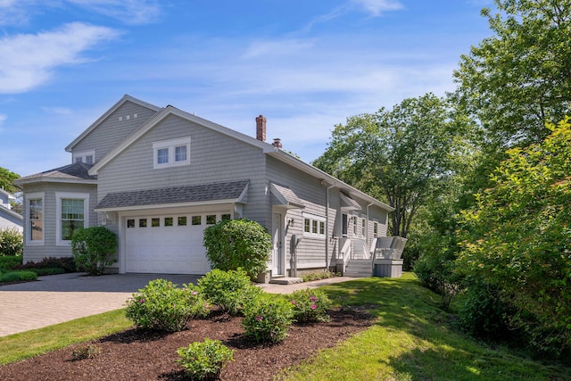 22 Saints Pl, Wells, ME 04090 - view of front of home featuring a chimney, decorative driveway, an attached garage, a front yard, and a shingled roof
