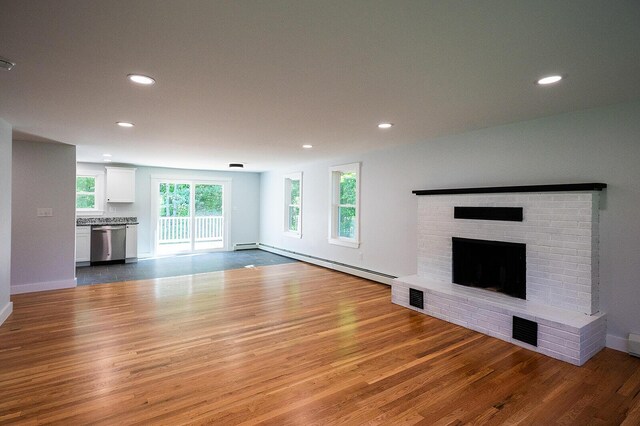 74 Hebron Rd, Paris, ME 04281 - unfurnished living room featuring a baseboard heating unit, wood finished floors, a brick fireplace, recessed lighting, and baseboards