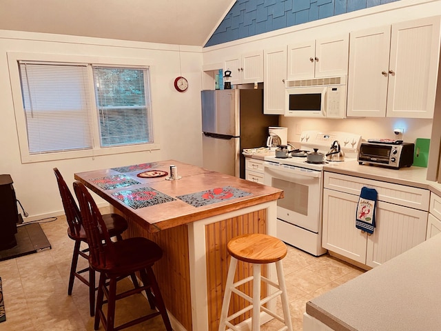 12 Spruce Gum Ln, Georgetown, ME 04548 - kitchen featuring white appliances, vaulted ceiling, a breakfast bar, light tile patterned flooring, and light countertops