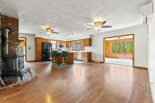 117 Taylor Woods Rd, Belgrade, ME 04917 - kitchen with appliances with stainless steel finishes, ceiling fan, a wood stove, and brown cabinetry
