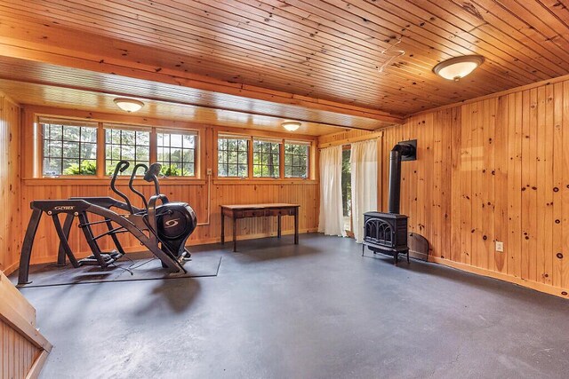 59 Lupine Dr, Belgrade, ME 04917 - exercise area featuring a wood stove, plenty of natural light, wood walls, and baseboards