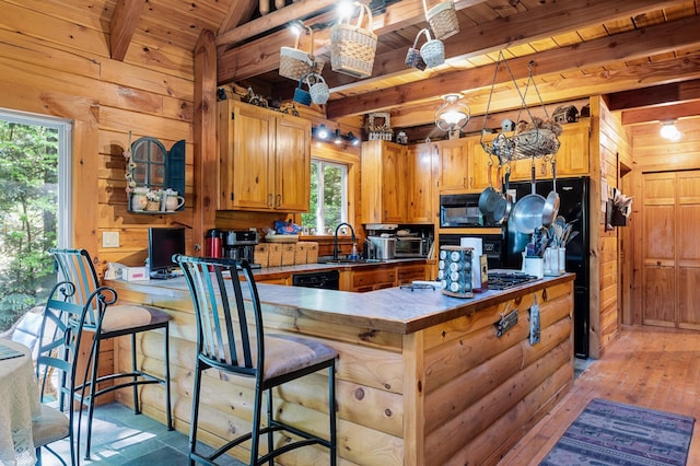 2451 Riverside Dr, Vassalboro, ME 04989 - kitchen with wood walls, wooden ceiling with exposed beams, black appliances, a peninsula, and a sink