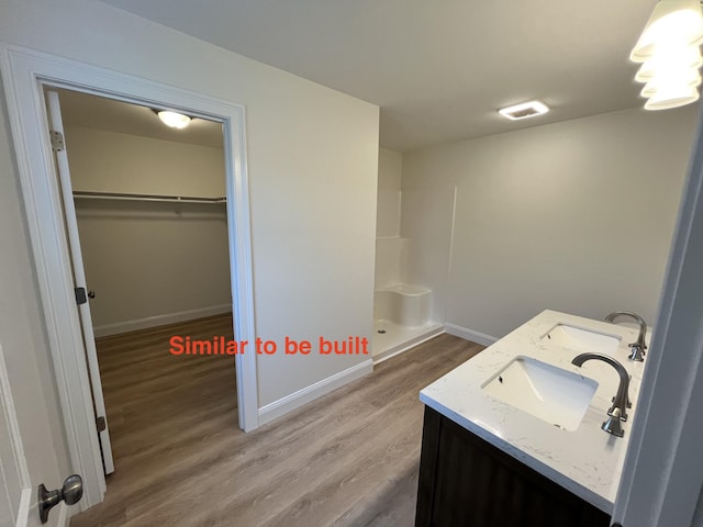 93 Union St, Orono, ME 04473 - full bathroom featuring wood finished floors, double vanity, walk in shower, a spacious closet, and baseboards