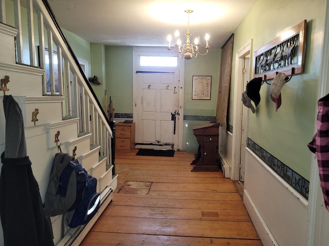627 Waterville Rd, Skowhegan, ME 04976 - foyer entrance featuring light wood finished floors, stairs, a chandelier, and a baseboard heating unit