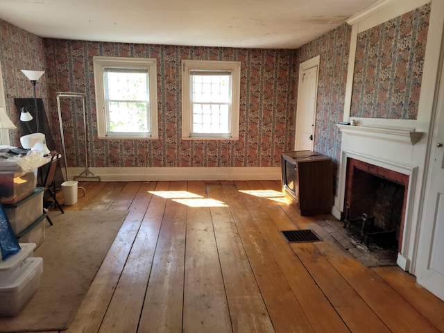627 Waterville Rd, Skowhegan, ME 04976 - unfurnished living room with hardwood / wood-style floors, a fireplace with flush hearth, wallpapered walls, and baseboards