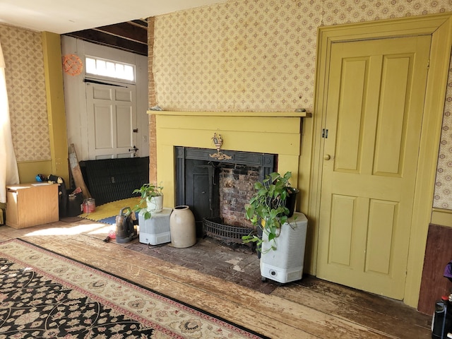 627 Waterville Rd, Skowhegan, ME 04976 - living area with wallpapered walls, a fireplace with raised hearth, and wood finished floors