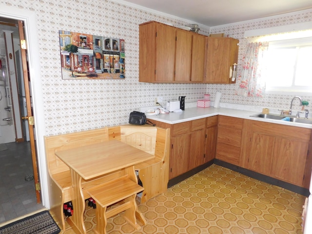 56 Allen St, Bangor, ME 04401 - kitchen featuring wallpapered walls, a sink, light countertops, crown molding, and brown cabinets