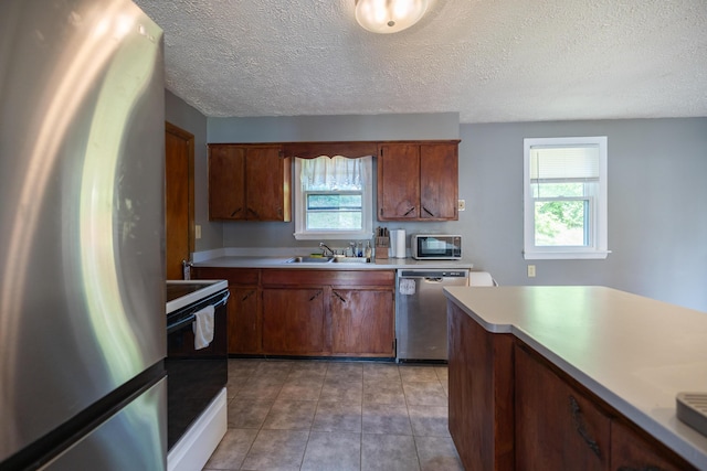 4 Scribner Cir, Lewiston, ME 04240 - kitchen with appliances with stainless steel finishes, light countertops, a textured ceiling, brown cabinetry, and light tile patterned floors