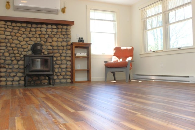 35 Harmon Notch Rd, Brownfield, ME 04010 - sitting room featuring a wall mounted AC, a baseboard heating unit, a wood stove, wood finished floors, and plenty of natural light