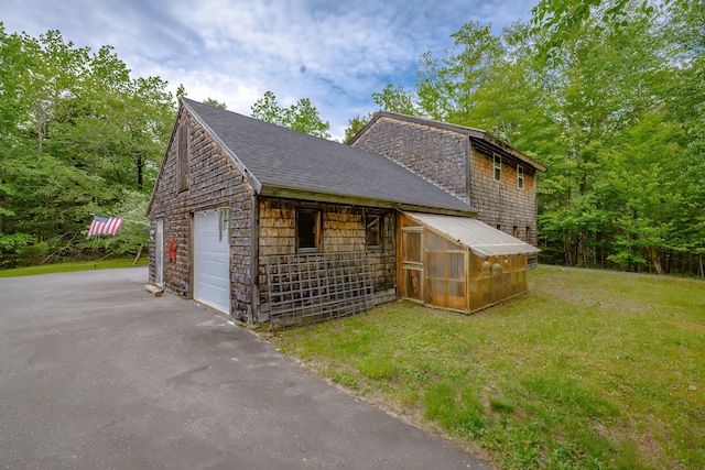 38 Johnson Cove Rd, Otis, ME 04605 - view of property exterior featuring an outbuilding, a shingled roof, a lawn, and driveway