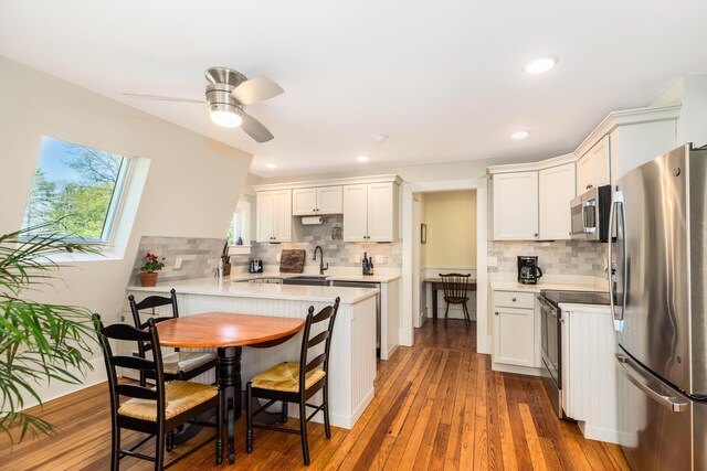 21 Fernald Ave Unit B, York, ME 03909 - kitchen with stainless steel appliances, a sink, a peninsula, a breakfast bar, and tasteful backsplash