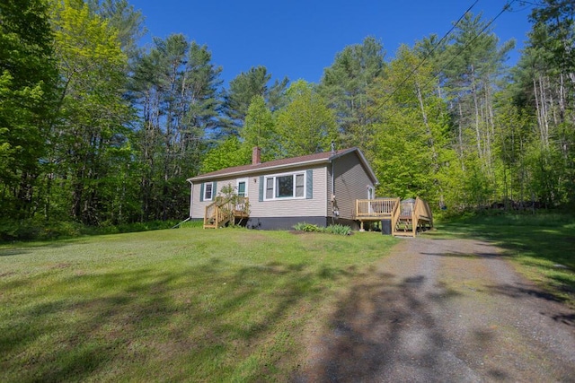 38 Greenridge Way, Jay, ME 04239 - view of front facade featuring a front lawn, a deck, a wooded view, and a chimney