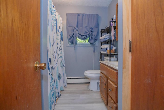 38 Greenridge Way, Jay, ME 04239 - bathroom with a baseboard heating unit, vanity, toilet, wood finished floors, and curtained shower