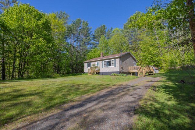 38 Greenridge Way, Jay, ME 04239 - view of front of home with a deck, a chimney, a front yard, and a wooded view