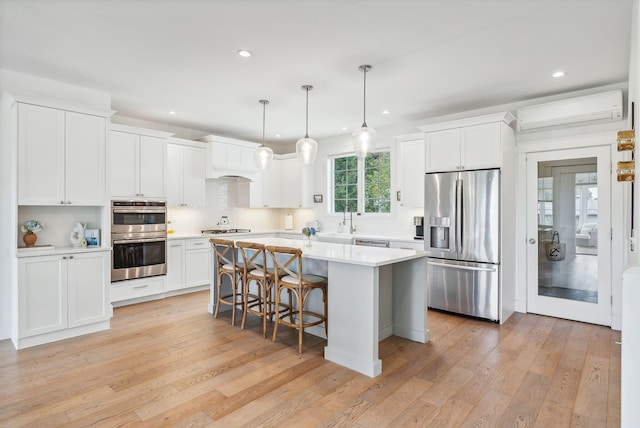 239A Foreside Rd ., Unit Falmouth, ME 04105 - kitchen with appliances with stainless steel finishes, a center island, a wall mounted air conditioner, recessed lighting, and white cabinets