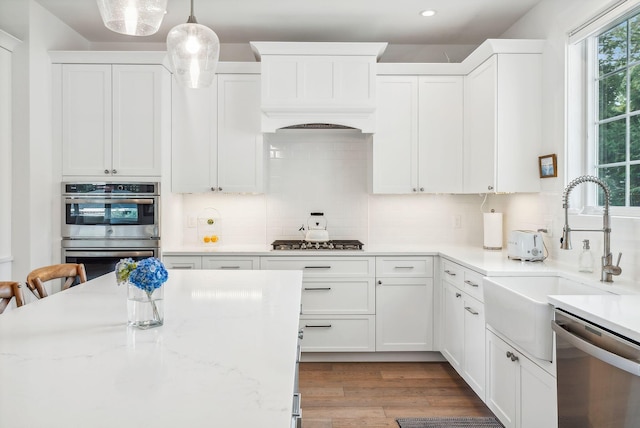 239A Foreside Rd ., Unit Falmouth, ME 04105 - kitchen with appliances with stainless steel finishes, backsplash, white cabinets, recessed lighting, and decorative light fixtures