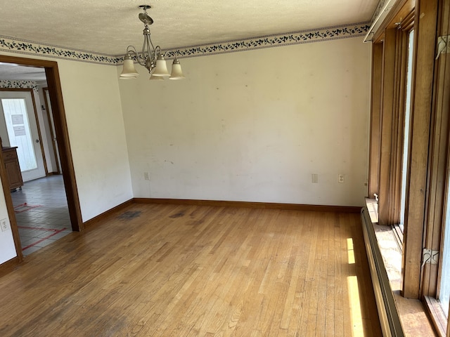 3 Harding Way, Kennebunk, ME 04043 - unfurnished room with a chandelier, light wood-style floors, baseboards, and a textured ceiling