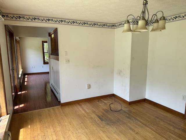 3 Harding Way, Kennebunk, ME 04043 - unfurnished dining area featuring a baseboard radiator, a chandelier, hardwood / wood-style floors, a textured ceiling, and baseboards