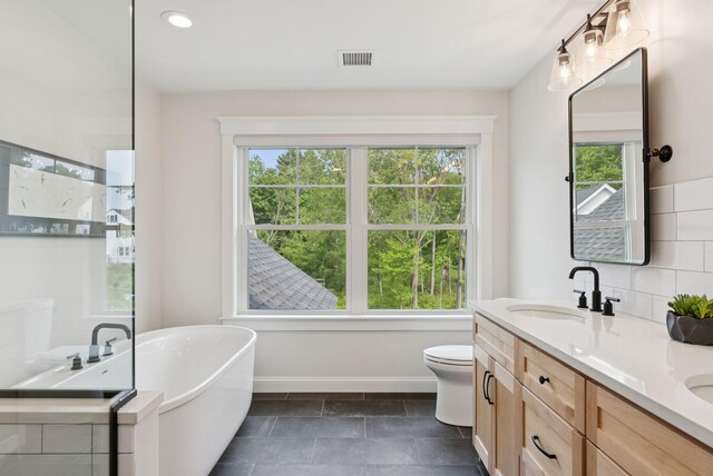 25 Benjamin Way, Portland, ME 04102 - bathroom with a freestanding tub, double vanity, baseboards, toilet, and tasteful backsplash